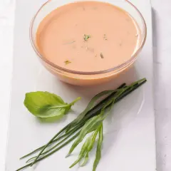 Schüssel mit cremigem French Dressing, garniert mit frischem Basilikum und Schnittlauch.