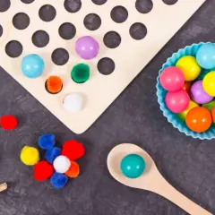 Juego heuristico materiales: pompones, bolas de colores y cuchara de madera para explorar texturas y formas.