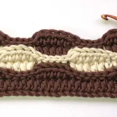 Punti all'uncinetto per copertine di lana, con filato marrone e beige che creano un motivo a onde.