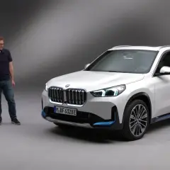 Dwóch mężczyzn obok białego BMW X1 elektryk.