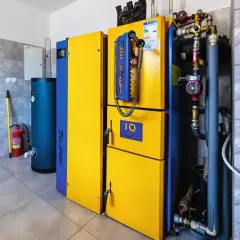 Nowoczesny piec gazowy 24kW, idealny do ogrzania domu o powierzchni do 240 m². Obok zasobnik wody i gaśnica.