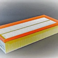 Filtro de aire rectangular con marco naranja y pliegues amarillos. Pregúntate cada cuanto se cambia filtro de aire para mantener tu motor limpio.