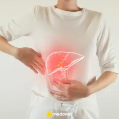 Kobieta trzyma się za brzuch, gdzie widoczny jest zarys wątroby z czerwonym podświetleniem. To może sugerować, że odczuwa objawy przeciążonej wątroby.