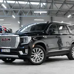 Czarny GMC Yukon Denali lśni w salonie samochodowym, gotowy na przygodę.