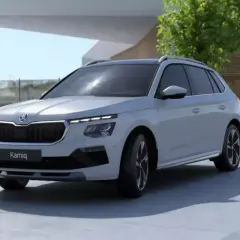 Jasnoszary SUV Skoda Kamiq z fabrycznym LPG prezentuje się nowocześnie na tle architektury i zieleni.