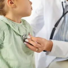 Lekarz podczas wizyty pediatrii osłuchuje małą pacjentkę stetoskopem.