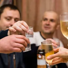 Ludzie wznoszą toast kieliszkami z wódką i szampanem.