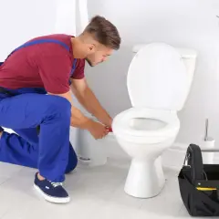 Idraulico al lavoro per sostituire guarnizione scarico WC. Attrezzi a portata di mano.
