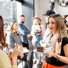 Kobiety jedzą ciasto w kawiarni, w tle inni ludzie.