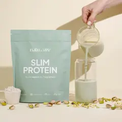 Natu.care Slim Protein o smaku pistacji, z miarką proszku i pistacjami. Płyn wlewany do szklanki.