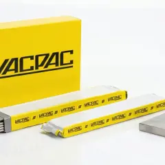 Żółte pudełko Vacpac i opakowania z różnymi rodzajami elektrod spawalniczych. Obok metalowy kolanko i płyta.