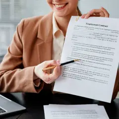 Persona sonriente muestra un contrato de empleo, lista para firmar contrato.