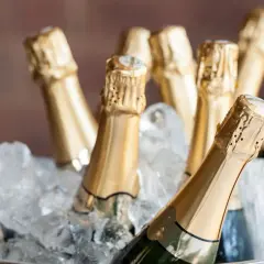 Mehrere Champagnerflaschen in goldenen Kapseln kühlen in einem Eisbad. Perfekt, um zu lernen, wie man Champagner trinkt.