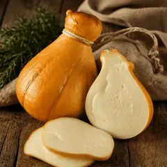 Queso scamorza ahumado, entero y cortado, con romero y tela rústica sobre madera.