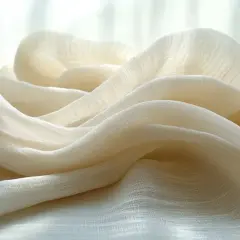Drapé de tissu léger et aérien, un mélange viscose polyester, aux teintes crème et aux reflets doux.
