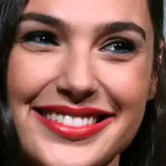 Zbliżenie na twarz Gal Gadot z szerokim uśmiechem i czerwonymi ustami.