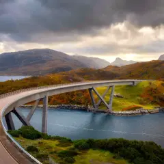 Un puente moderno cruza un fiordo escocés, con colinas otoñales y cielos dramáticos. La ruta 500 escocia ofrece vistas espectaculares.