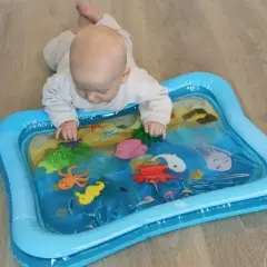 Niemowlę bawi się na macie wodnej z morskimi stworzeniami. Mata wodna dla niemowlaka od kiedy? Od pierwszych miesięcy życia, wspiera rozwój.