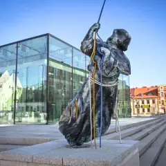 Rzeźba na rynku w Częstochowie, z nowoczesnym budynkiem w tle.