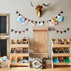 Uroczy pokój dziecięcy z drewnianymi regałami do przechowywania zabawek, tablicami i dziełami sztuki na ścianie.
