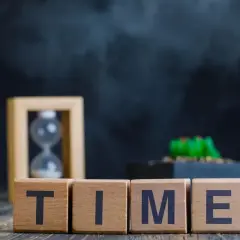 Blocchi di legno con la parola TIME, clessidra e pianta. È mezzanotte, il tempo scorre.