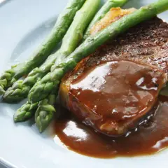 Un délicieux steak servi avec une sauce onctueuse, des asperges croquantes et des pommes de terre nouvelles. Un plat parfait pour un dîner savoureux.