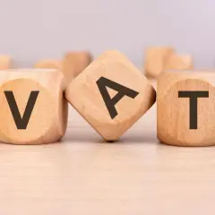 Drewniane klocki z literami V, A, T tworzą słowo VAT. To ważny element każdego formularza zaw-fa.