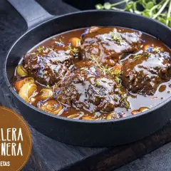 Carrilleras de ternera estofadas en salsa oscura, con trozos de verdura y hierbas. ¡Un clásico de la receta de la abuela!