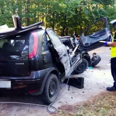 Policjant spisuje raport przy wraku Opla Corsy po wypadku. Czy to rejestracja GKS jakie miasto?