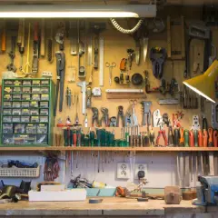 Un agencement d'atelier bricolage bien organisé, avec des outils suspendus et des tiroirs de rangement remplis.