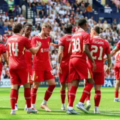Piłkarze Liverpoolu, mistrzowie Anglii, świętują na boisku. Widać numery 11, 14, 8, 38, 21 i 2.