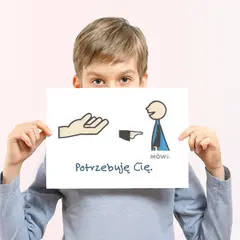 Chłopiec trzyma tabliczkę z rysunkiem dłoni, postaci i napisem "Potrzebuję Cię".