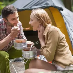 Para na kempingu dzieli się posiłkiem z metalowych pojemników. Idealne jedzenie na wyjazd bez lodówki, smakuje wybornie w otoczeniu natury.