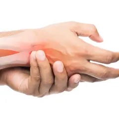 Mano che si tiene il polso con aree rosse che indicano dolore. Possibili cause di dolori alle caviglie e polsi.