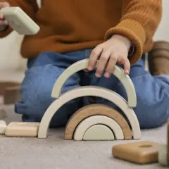 Niño jugando con bloques de madera, creando un arcoíris. Un ejemplo del sistema montessori para el desarrollo infantil.