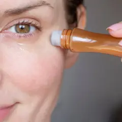 Kobieta aplikuje serum pod oczy, by zredukować widoczne zmarszczki pod oczami.