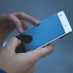 Dłonie trzymające smartfon. Zastanawiasz się, jak odzyskać telefon zatrzymany przez policję?