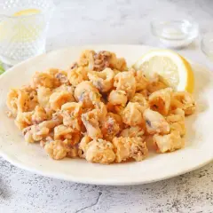 Un plato generoso de chipirones fritos crujientes, adornado con una rodaja de limón.