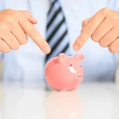 Manos señalan alcancía rosa. Es legal pedir un aval bancario para un alquiler, una garantía para tu inversión.