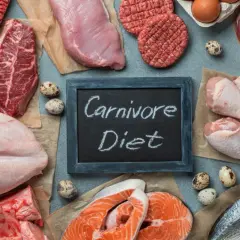 Różnorodne mięsa, ryby i jaja na stole. Tabliczka z napisem "Carnivore Diet" sugeruje, że to inspiracja dla osób szukających efektów diety karniwora.