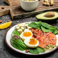 Talerz z łososiem, jajkami, awokado, serem i szpinakiem. Idealne składniki na śniadanie zgodne z dieta keto zasady.