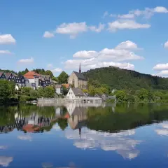 Idyllische Häuserzeile mit Kirche am Ufer des Beyenburger Stausees. Perfekt für eine entspannte Rundweg-Tour.
