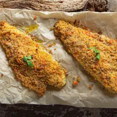Filetti di orata in padella gratinati, dorati e croccanti, guarniti con erbe fresche.