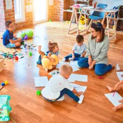Niños de guardería de 2 años dibujan y juegan en el suelo.
