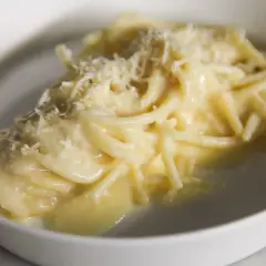 Un piatto di pasta burro e parmigiano, cremoso e invitante, con una spolverata di formaggio grattugiato.