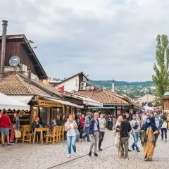 Tętniący życiem bazar w Bośni i Hercegowinie. Ludzie spacerują wśród straganów i kawiarni, odkrywając lokalne atrakcje.