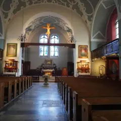 Wnętrze kościoła z ławkami, ołtarzem i krzyżem.