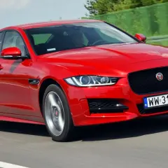 Czerwony Jaguar XE w ruchu na drodze.