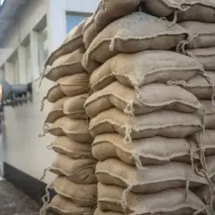 Stos worków cementu na palecie, gotowy do budowy. Widać ich wiele, trudno policzyć ile worków cementu na palecie.