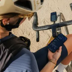 Kolarz sprawdza aplikację na rowerze, analizując dane treningowe na telefonie.